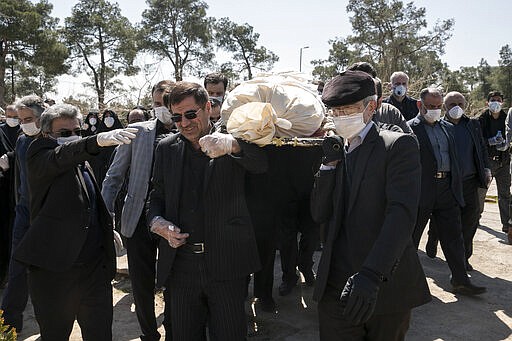 Mourners wearing face masks and gloves carry the body of former politburo official in the Revolutionary Guard Farzad Tazari, who died Monday after being infected with the new coronavirus, at the Behesht-e-Zahra cemetery just outside Tehran, Iran, Tuesday, March 10, 2020. Iran is the hardest-hit country in the Mideast by the new coronavirus, which sickens but largely doesn't kill those afflicted. (Mahmood Hosseini/Tasnim News Agency via AP)