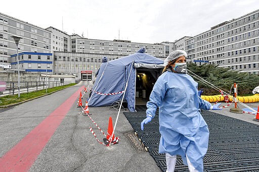 FILE - In this Feb. 29, 2020 file photo, a paramedic walks out of a tent that was set up in front of the emergency ward of the Cremona hospital, northern Italy. Italian doctors celebrated one small victory in their battle against the coronavirus Monday after Patient No. 1, a 38-year-old named Mattia was moved out of intensive care. But in the rest of hard-hit northern Italy, the virus' spread was growing so exponentially that doctors spoke of choices war-time triage medics make in deciding who lives and who dies, and who get access to the limited number of ICU beds. (Claudio Furlan/Lapresse via AP, file)