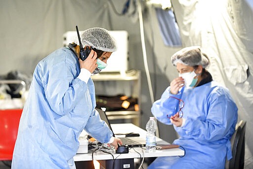 FILE - In this Saturday, Feb. 29, 2020 file photo, paramedics work in a tent that was set up outside the hospital of Cremona, northern Italy. Italian doctors celebrated one small victory in their battle against the coronavirus Monday after Patient No. 1, a 38-year-old named Mattia was moved out of intensive care. But in the rest of hard-hit northern Italy, the virus' spread was growing so exponentially that doctors spoke of choices war-time triage medics make in deciding who lives and who dies, and who get access to the limited number of ICU beds. (Claudio Furlan/Lapresse via AP)