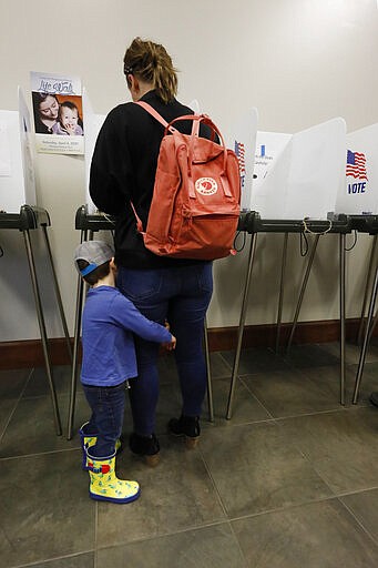 Charlie Weiland, 3, hugs his mother Courtney Weiland's leg as she votes in the parties primaries, in Ridgeland, Miss., Tuesday, March 10, 2020. (AP Photo/Rogelio V. Solis)