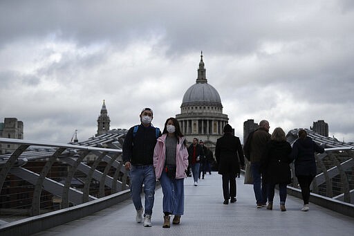 People wearing face masks walk across the Millennium footbridge backdropped by the dome of St Paul's Cathedral in London, Tuesday, March 10, 2020. Starkly illustrating the global east-to-west spread of the new coronavirus, Italy began an extraordinary, sweeping nationwide travel ban on Tuesday while in China, the diminishing threat prompted the president to visit the epicenter and declare: &quot;&quot;We will certainly defeat this epidemic.&quot; (AP Photo/Matt Dunham)