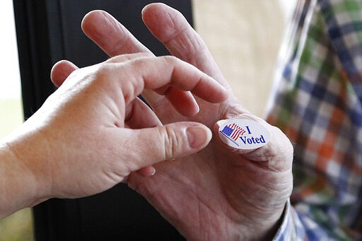 A voter accepts an &quot;I Voted&quot; sticker from Ridgeland, Miss., precinct worker Cliff Smith, right, as she exits after voting in the party presidential primary, Tuesday, March 10, 2020. (AP Photo/Rogelio V. Solis)