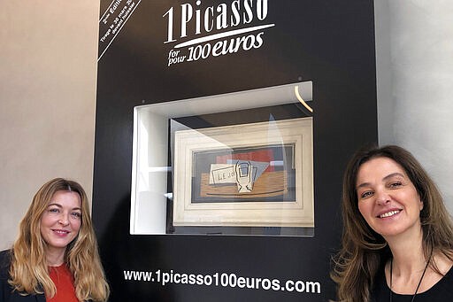 In this photo taken on Tuesday, March 3, 2020, art historian Arabelle Reille, left, and television producer Peri Cochin pose in the Picasso Museum in Paris, in front of &quot;Nature Morte,&quot; which Pablo Picasso painted in 1921. The two women are organizing a raffle for charity of the oil on canvas that belongs to billionaire art collector David Nahmad. A still life that Picasso painted in 1921 is being raffled off for charity in Paris this month with tickets at 100 euros each. (AP Photo/John Leicester)