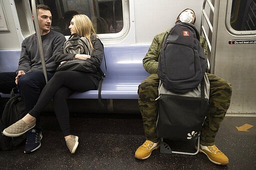 A commuter wears a face mask while riding the subway, Tuesday, March 10, 2020, in New York. For most people, the new coronavirus causes only mild or moderate symptoms, such as fever and cough. For some, especially older adults and people with existing health problems, it can cause more severe illness, including pneumonia. The vast majority of people recover from the new virus. (AP Photo/Mary Altaffer)