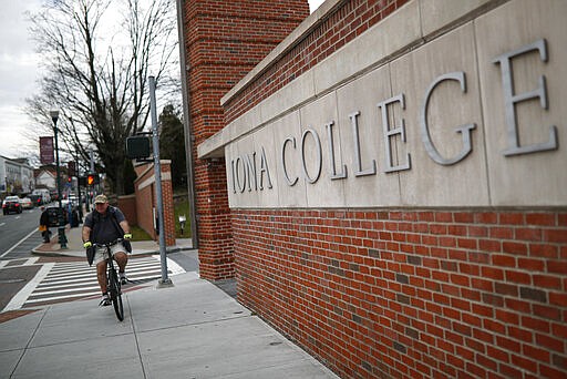 Pedestrians pass Iona College, Tuesday, March 10, 2020, in New York. State officials are shuttering schools and houses of worship for two weeks in part of the New York City suburb New Rochelle and sending the National Guard there to help respond to what appears to be the nation's biggest cluster of coronavirus cases. (AP Photo/John Minchillo)