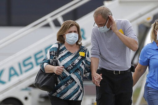 Passengers from the Grand Princess, a cruise ship carrying multiple people who have tested positive for COVID-19, walk on a tarmac before boarding a chartered plane in Oakland, Calif., Tuesday, March 10, 2020. The passengers on the flight are going to San Antonio to be quarantined at Lackland Air Force Base. (AP Photo/Jeff Chiu)