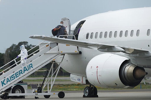 A passengers from the Grand Princess, a cruise ship carrying multiple people who have tested positive for COVID-19, boards a chartered plane in Oakland, Calif., Tuesday, March 10, 2020. The passengers on the flight are going to San Antonio to be quarantined at Lackland Air Force Base. (AP Photo/Jeff Chiu)