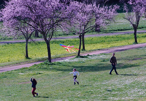 FILE - In this March 7, 2020, file photo, people enjoy the good weather in a park in downtown Rome. As outbreaks of the new virus that first emerged in China continue to spread in countries, particularly those experiencing winter, one of the biggest unanswered questions is how COVID-19 will behave in warmer weather. (AP Photo/Domenico Stinellis, File)