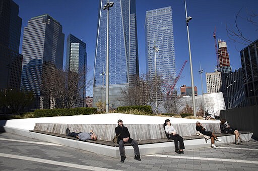 FILE - In this March 9, 2020, file photo, people rest in the sunshine in the World Trade Center's Liberty Park.   As outbreaks of the new virus that first emerged in China continue to spread in countries, particularly those experiencing winter, one of the biggest unanswered questions is how COVID-19 will behave in warmer weather. (AP Photo/Mark Lennihan, File)