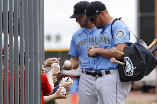 Seattle Mariners' Connor Lien, left, and Mitch Nay stop to sign autographs before a spring training baseball game against the Los Angeles Angels on Tuesday, March 10, 2020, in Peoria, Ariz. (AP Photo/Elaine Thompson)