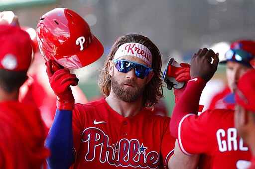 Philadelphia Phillies' Bryce Harper is met in the dugout after being pulled for a pinch runner during a spring training baseball game against the New York Yankees Monday, March 9, 2020, in Clearwater, Fla. (AP Photo/Carlos Osorio)