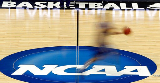 FILE - In this March 14, 2012, file photo, a player runs across the NCAA logo during practice at the NCAA tournament college basketball in Pittsburgh. The NCAA Board of Governors took the first step Tuesday, Oct. 29, 2019, toward allowing athletes to cash in on their fame, voting unanimously to clear the way for the amateur athletes to &quot;benefit from the use of their name, image and likeness.&quot; (AP Photo/Keith Srakocic, File)