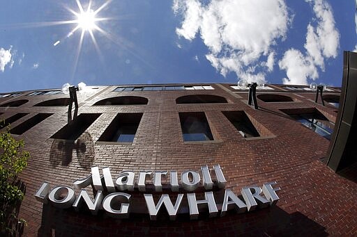 FILE - This July 9, 2012, photo made with a fish-eye lens shows the exterior of the Marriott Long Wharf in Boston. Seventy of Massachusetts' first 92 confirmed coronavirus cases have been linked to a meeting of Biogen executives that was held at the hotel in late February 2020. For most people, the virus causes only mild or moderate symptoms, such as fever and cough. For some, especially older adults and people with existing health problems, it can cause more severe illness, including pneumonia. The vast majority of people recover from the new virus. (AP Photo/Elise Amendola, File)