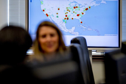 A monitor displaying arrests made across the country as part of &quot;Project Python&quot; is visible behind Drug Enforcement Administration agents and intelligence analysts gathering information from field operations across the country at their command center in Chantilly, Va., Wednesday, March 11, 2020.  (AP Photo/Andrew Harnik)