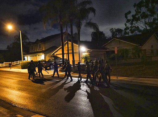 DEA agents move in on a residential house during an arrest of a suspected drug trafficker on Wednesday, March 11, 2020 in Diamond Bar, Calif. In early-morning raids Wednesday, federal agents fanned out across the U.S., culminating a six-month investigation with the primary goal of dismantling the upper echelon of the Jalisco New Generation Cartel, known as CJNG. (AP Photo/Richard Vogel)