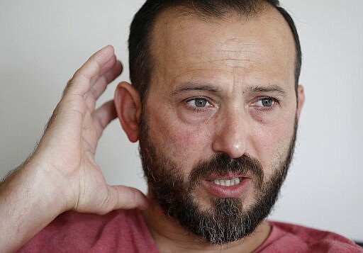 In this Tuesday, Feb. 25, 2020, photo, Al Noor mosque shooting survivor Temel Atacocugu gestures during an interview at his home in Christchurch, New Zealand. When the gunman walked into the mosque, Atacocugu was kneeling for Friday prayers. He looked up into the man's face, thinking he was a police officer because of his paramilitary outfit. Time slowed. Temel saw a puff of smoke come from the raised gun, felt a bullet smash into his teeth, and thought: &quot;Oh, my God, I'm dying.&quot; (AP Photo/Mark Baker)