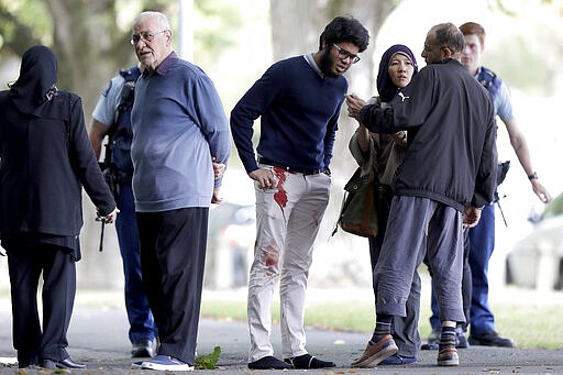 FILE - In this March 15, 2019, file photo, people stand across a road from the Al Noor mosque following a mass shooting in central Christchurch, New Zealand. On Sunday, March 15, 2020, New Zealand will commemorate the 51 people who were killed in the attacks. (AP Photo/Mark Baker, File)