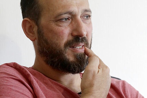 In this Tuesday, Feb. 25, 2020, photo, Al Noor mosque shooting survivor Temel Atacocugu gestures to where the first bullet hit him during an interview at his home in Christchurch, New Zealand. When the gunman walked into the mosque, Atacocugu was kneeling for Friday prayers. He looked up into the man's face, thinking he was a police officer because of his paramilitary outfit. Time slowed. Temel saw a puff of smoke come from the raised gun, felt a bullet smash into his teeth, and thought: &quot;Oh, my God, I'm dying.&quot; (AP Photo/Mark Baker)