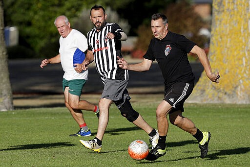 In this Wednesday, Feb. 26, 2020, photo, Al Noor mosque shooting survivor Temel Atacocugu, center, gestures during a social game of soccer in Christchurch, New Zealand. When the gunman walked into the mosque, Atacocugu was kneeling for Friday prayers. He looked up into the man's face, thinking he was a police officer because of his paramilitary outfit. Time slowed. Temel saw a puff of smoke come from the raised gun, felt a bullet smash into his teeth, and thought: &quot;Oh, my God, I'm dying.&quot; (AP Photo/Mark Baker)