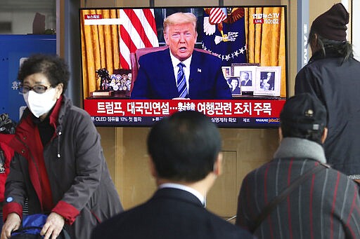 People watch a TV screen showing a live broadcast of U.S. President Donald Trump's speech at the Seoul Railway Station in Seoul, South Korea, Thursday, March 12, 2020. Trump announced he is cutting off travel from Europe to the U.S. and moving to ease the economic cost of a viral pandemic that is roiling global financial markets and disrupting the daily lives of Americans. The Korean letters read: &quot;Trump national speech.&quot; (AP Photo/Ahn Young-joon)