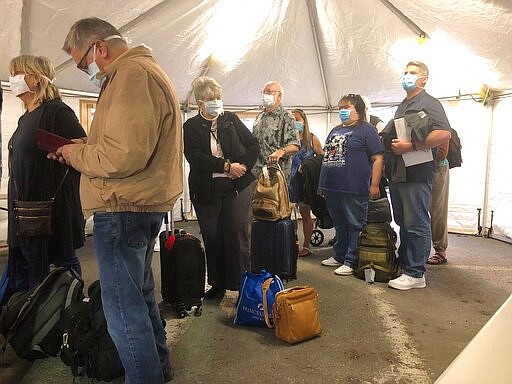 This photo provided by Laurie Miller shows Grand Princess cruise ship passengers being screened inside a tent, Tuesday, March 10, 2020, in Oakland, Calif., before boarding a bus that will take them to a military base for quarantine. California Gov. Gavin Newsom urged the state's nearly 40 million residents to avoid sporting events, concerts and large gatherings to prevent the spread of the coronavirus and adamantly warned the elderly to stay away from cruise ships as he pondered measures to restrict cruise travel off the California coast. (Laurie Miller via AP)