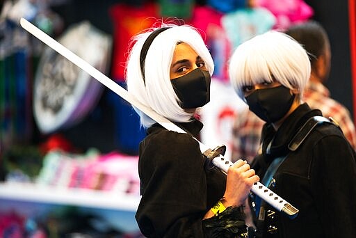 FILE -  In this March 5, 2020, file, photo, two women wearing masks dressed as sword-wielding anime characters pose for a photograph at the Middle East Film &amp; Comic Con in Dubai, United Arab Emirates. he United Arab Emirates will shut down its schools for four weeks as the coronavirus threatens global oil prices, airlines and Dubai&#146;s upcoming Expo 2020 world&#146;s fair. (AP Photo/Jon Gambrell, File)