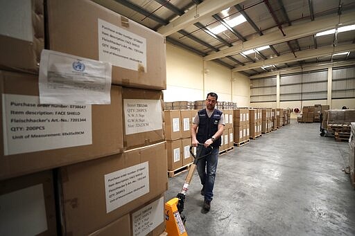 FILE -  In this March 5, 2020, file, photo, a worker pulls a cart of coronavirus aid items being prepared for shipment, at a World Health Organization, WHO, facility, part of the International Humanitarian City, in Dubai, United Arab Emirates. The United Arab Emirates will shut down its schools for four weeks as the coronavirus threatens global oil prices, airlines and Dubai&#146;s upcoming Expo 2020 world&#146;s fair. (AP Photo/Kamran Jebreili, File)