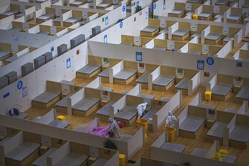 In this Sunday, March 8, 2020, photo released by Xinhua News Agency, workers in protective suits clean up a makeshift hospital which converted from a sports venue after it officially closed in Wuhan in central China's Hubei province. The province at the center of China's virus outbreak is allowing factories and some other businesses to reopen in a new sign Beijing believes the disease that devastated its economy is being brought under control. (Xiao Yijiu/Xinhua via AP)