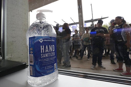 A large bottle of hand sanitizer sits next to a door as fans prepare to enter the arena for an NBA basketball game between the San Antonio Spurs and the Dallas Mavericks in San Antonio, Tuesday, March 10, 2020. (AP Photo/Eric Gay)