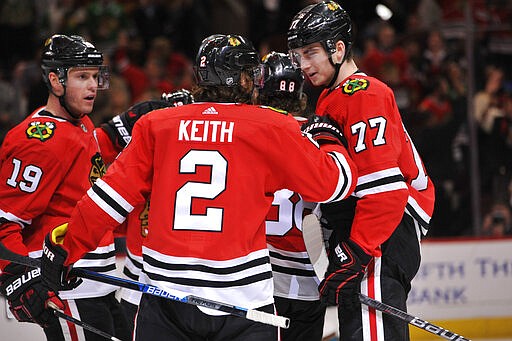 Chicago Blackhawks' Duncan Keith (2) celebrates with teammates Kirby Dach (77) and Jonathan Toews (19) after scoring a goal during the second period of an NHL hockey game against the San Jose Sharks Wednesday, March 11, 2020, in Chicago. (AP Photo/Paul Beaty)