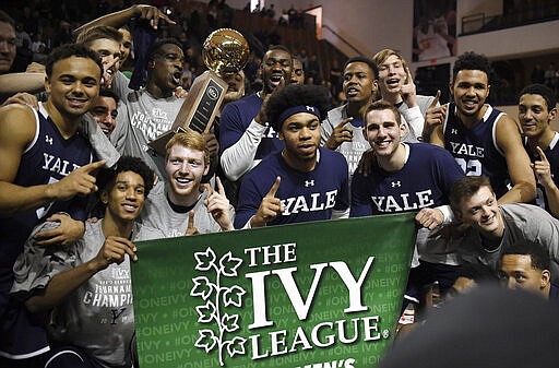 FILE - In this March 17, 2019, file photo, Yale players pose for a photograph with the championship trophy after defeating Harvard in an NCAA college basketball game for the Ivy League championship at Yale University in New Haven, Conn.  The Ivy League on Tuesday, March 10, 2020, canceled its men's and women's basketball tournaments because of concerns about the spread of coronavirus. The four-team tournaments were scheduled to be played Friday through Sunday at Lavietes Pavilion in Cambridge. The Ivy League instead will award its automatic NCAA Tournament bids to the regular-season champions, the Princeton women and Yale men. (AP Photo/Jessica Hill, File)