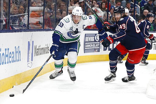 Vancouver Canucks' Bo Horvat, left, and Columbus Blue Jackets' Ryan MacInnis chase a loose puck during the third period of an NHL hockey game Sunday, March 1, 2020, in Columbus, Ohio. The Blue Jackets defeated the Canucks 5-3. (AP Photo/Jay LaPrete)