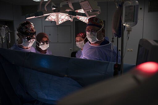 Dr. Vitaly Dedovich, left, Dr. William Novick, right, and Nurse Martina Pavanic of the Novick Cardiac Alliance medical team check the monitors with Dr. Fatima Alhony, center left, at the end of an open heart surgery on a 1-year-old boy at the Tajoura National Heart Center in Tripoli, Libya, on Feb. 27, 2020. While still a resident, Novick began recruiting experts to help him trek to places where treatable heart disease means death due to a shortage of specialists and other restrictions. (AP Photo/Felipe Dana)