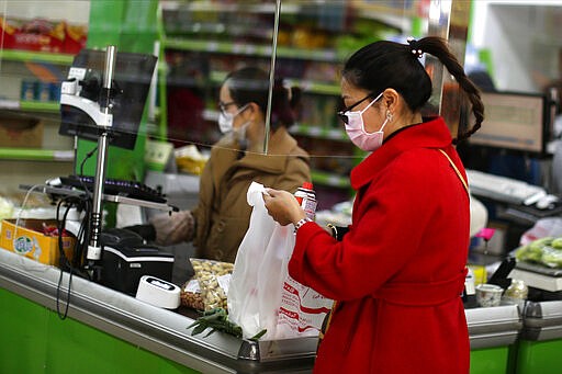 Customers wear face masks in a supermarket in Madrid, Spain, Wednesday, March 11, 2020. Spain's health minister on Monday announced a sharp spike in coronavirus cases in and around the national capital, Madrid, and said all schools in the region, including kindergartens and universities, will close for two weeks from Wednesday. For most people, the new coronavirus causes only mild or moderate symptoms, such as fever and cough. For some, especially older adults and people with existing health problems, it can cause more severe illness, including pneumonia. (AP Photo/Manu Fernandez)