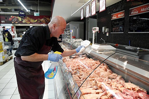 An employee disinfects the glass cover of a butcher counter to prevent the spread of the novel coronavirus in a food store in Budapest, Hungary, Wednesday, March 11, 2020. For most people, the new coronavirus causes only mild or moderate symptoms, such as fever and cough. For some, especially older adults and people with existing health problems, it can cause more severe illness, including pneumonia. (Tamas Kovacs/MTI via AP)