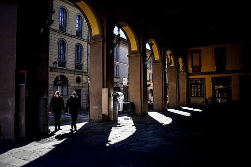 People wear masks as they walk in Codogno, in the region of Lombardia, northern Italy, Wednesday, March 11, 2020. The Lombardy cluster of COVID-19 was first registered in the tiny town of Codogno on Feb. 19, when the first patient tested positive and has been a red zone until the end of seclusion and return of production in the recent days. For most people, the new coronavirus causes only mild or moderate symptoms, such as fever and cough. For some, especially older adults and people with existing health problems, it can cause more severe illness, including pneumonia. (Claudio Furlan/LaPresse via AP)