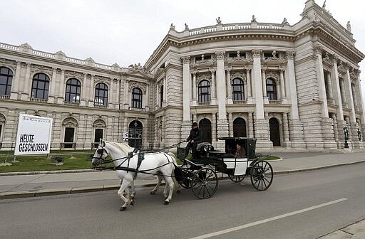 A Fiaker coach passes in front of a poster is written &quot; closed today&quot; the Burgtheater in Vienna, Austria, Wednesday, March 11, 2020. The culture activities in Austria will be closed at least until the end of March. For most people, the new coronavirus causes only mild or moderate symptoms, such as fever and cough. For some, especially older adults and people with existing health problems, it can cause more severe illness, including pneumonia. (AP Photo/Ronald Zak)