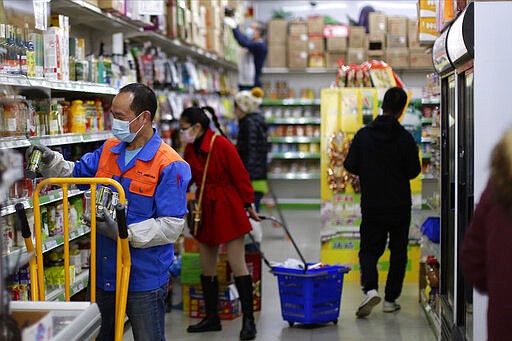 Staff and shoppers wear face masks inside a supermarket in Madrid, Spain, Wednesday, March 11, 2020. Spain's health minister on Monday announced a sharp spike in coronavirus cases in and around the national capital, Madrid, and said all schools in the region, including kindergartens and universities, will close for two weeks from Wednesday. For most people, the new coronavirus causes only mild or moderate symptoms, such as fever and cough. For some, especially older adults and people with existing health problems, it can cause more severe illness, including pneumonia. (AP Photo/Manu Fernandez)