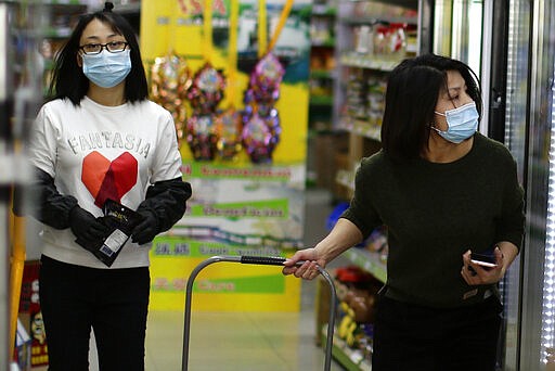 Customers wear face masks inside a supermarket in Madrid, Spain, Wednesday, March 11, 2020. Spain's health minister on Monday announced a sharp spike in coronavirus cases in and around the national capital, Madrid, and said all schools in the region, including kindergartens and universities, will close for two weeks from Wednesday. For most people, the new coronavirus causes only mild or moderate symptoms, such as fever and cough. For some, especially older adults and people with existing health problems, it can cause more severe illness, including pneumonia. (AP Photo/Manu Fernandez)