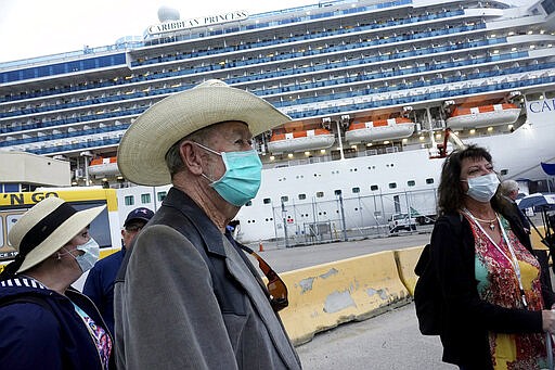 Jana Harrelson, left, Ronny Young, and Karla Weston, right, all of Port St. Joe, Florida, disembark from the Caribbean Princess at Port Everglades in Fort Lauderdale, Fla., Wednesday, March 11, 2020. The cruise ship was been given federal permission to dock in Florida after testing of two crew members cleared them of the new coronavirus and U.S. health officials lifted a &#147;no sail&quot; order. (Joe Cavaretta/South Florida Sun-Sentinel via AP)