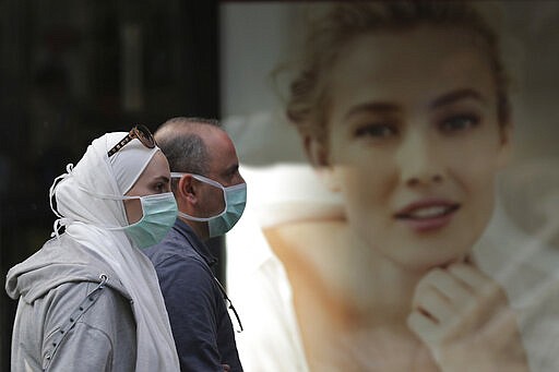 People wear masks to help protect themselves from the new coronavirus on Hamra street in Beirut, Lebanon, Wednesday, March 11, 2020. For most people, the new coronavirus causes only mild or moderate symptoms, such as fever and cough. For some, especially older adults and people with existing health problems, it can cause more severe illness, including pneumonia. (AP Photo/Hassan Ammar)