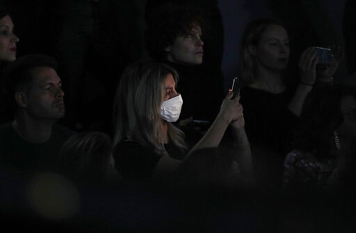 FILE - In this Feb. 23, 2020, file photo, a woman wearing a sanitary mask takes photos during the Dolce &amp; Gabbana women's fall-winter 2020-21 show, in Milan, Italy. Italian Premier Giuseppe Conte's decision to lock down his entire country brought some welcome clarity to life in Italy after weeks of uncertainty about how to behave in a time of coronavirus, according to Associated Press reporter Colleen Barry. (AP Photo/Antonio Calanni, File)