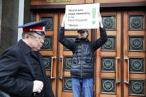 A member of the liberal Yabloko Party holds a poster reading: &quot;You need to change the brain, not the constitution!&quot; as he stages a one-man picket at the State Duma, the Lower House of the Russian Parliament in Moscow, Russia, Wednesday, March 11, 2020. The Russian parliament has approved a sweeping constitutional reform that will allow President Vladimir Putin to stay in power for another 12 years after his current term ends in 2024. Wednesday's vote was the third and final reading. (AP Photo/Pavel Golovkin)