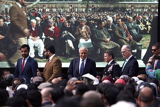 FILE- In this March 9, 2020, file photo, Washington's peace envoy Zalmay Khalilzad, center, arrives for inauguration ceremony for Ashraf Ghani at the presidential palace in Kabul, Afghanistan. After a series of delays, Afghan President Ashraf Ghani issued a decree early Wednesday, March 11, 2020, promising to release 1,500 Taliban prisoners as a goodwill gesture to get intra-Afghan negotiations started, even though a deal signed by the United States and the Taliban calls for the release of up to 5,000 prisoners ahead of the much sought after negotiations.(AP Photo/Rahmat Gul, File)