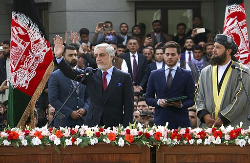 In this Monday, March 9, 2020, photo, Afghanistan's Abdullah Abdullah, front left, greets his supporters after being sworn in as president in Kabul, Afghanistan. Washington moved forward Tuesday on its peace deal with the Taliban, launching its troop withdrawal, while praising Afghanistan's newly installed President Ashraf Ghani's promise to proceed with a Taliban prisoner release as well as cobble together a team to start negotiations with the insurgent group. But the dueling presidential inaugurations a day earlier with Ghani's rival, Abdullah Abdullah also being sworn in as president is indicative of the uphill task facing Washington's peace envoy Zalmay Khalilzad as he tries to get Afghanistan's bickering leadership to come together.  (AP Photo)