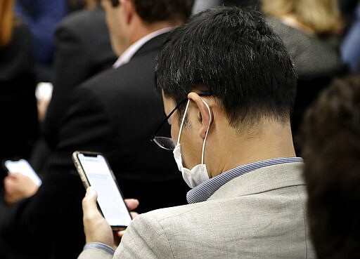 A journalist wears face mask as he waits for New Zealand Prime Minister Jacinda Ardern to address a news conference in Christchurch, New Zealand, Friday, March 13, 2020. Events to mark the death of multiple people who were killed and dozens injured when a gunman attacked two mosques in Christchurch March 15, 2019, begin today. (AP Photo/Mark Baker)