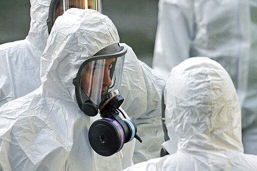 Workers from a Servpro disaster recovery team wearing protective suits and respirators line up before entering the Life Care Center in Kirkland, Wash. to begin cleaning and disinfecting the facility, Wednesday, March 11, 2020, near Seattle. The nursing home is at the center of the outbreak of the COVID-19 coronavirus in Washington state. (AP Photo/Ted S. Warren)