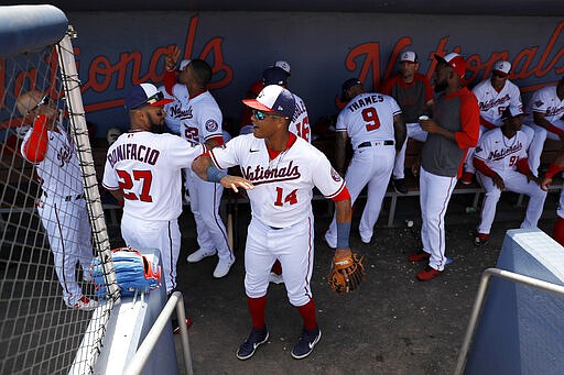 Washington Nationals center fielder Emilio Bonifacio (27) and second baseman Starlin Castro (14) tap arms as they get ready in the dugout prior to a spring training baseball game against the New York Yankees, Thursday, March 12, 2020, in West Palm Beach, Fla. Major League Baseball is delaying the start of its season by at least two weeks because of the coronavirus outbreak and has suspended the rest of its spring training game schedule. (AP Photo/Julio Cortez)