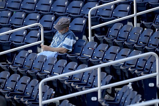 A lingering fan sits behind home plate after a spring training baseball game between the New York Yankees and the Washington Nationals, Thursday, March 12, 2020, in West Palm Beach, Fla. (AP Photo/Julio Cortez)