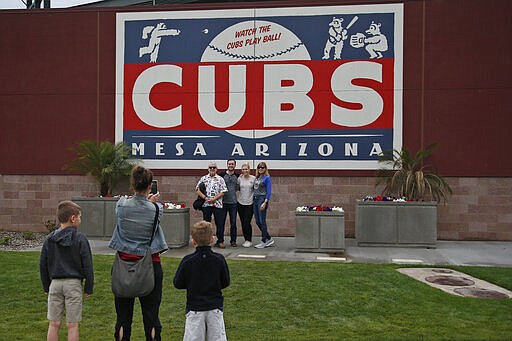 Fans pose for photographs outside the spring training site of the Chicago Cubs,, Thursday, March 12, 2020, at Sloan Park in Mesa, Ariz. Major League Baseball has announced that it is suspending the remainder of its spring training game schedule. (AP Photo/Sue Ogrocki)